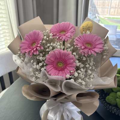 Pink gerbera daisy bouquet with baby's breath in beige wrap