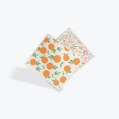 Two patterned square napkins with orange fruit and floral prints