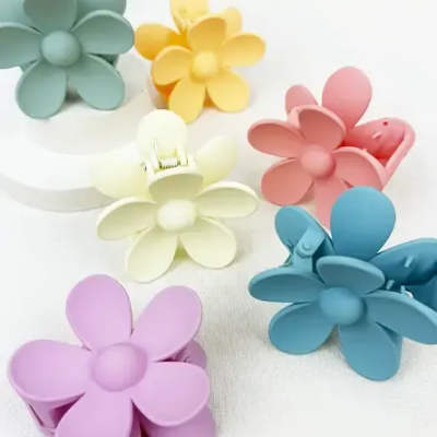 Pastel flower-shaped hair clips arranged on a white surface