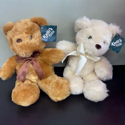 Two plush teddy bears with ribbon bows, one tan and one white