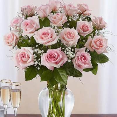 Pink roses arranged in a clear glass vase with baby's breath