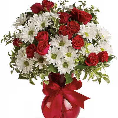 Red roses and white daisies in a red glass vase with a ribbon