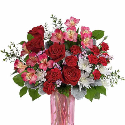 Bouquet of red roses and pink flowers in a pink glass vase