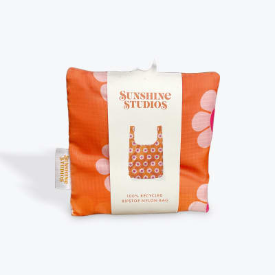 Folded orange floral tote bag with packaging label