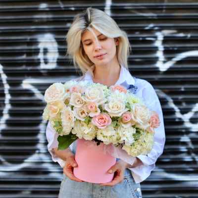 Woman holding a pink box of pale roses and hydrangeas
