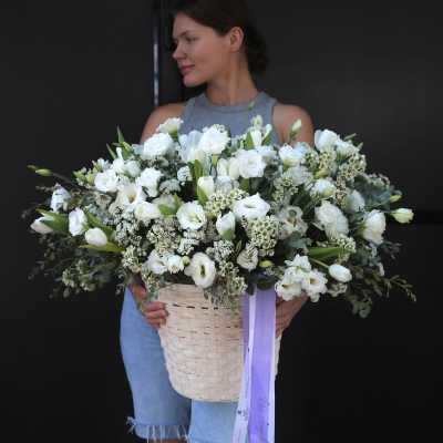 Woman holding a large white flower basket with a lavender ribbon