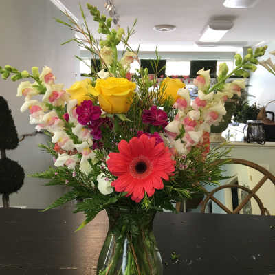 Mixed bouquet in a glass vase with yellow roses and pink gerbera daisies