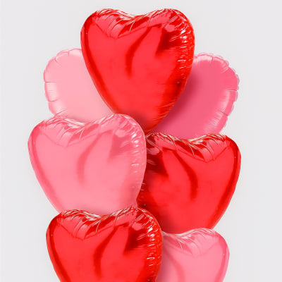 Cluster of red and pink heart-shaped balloons with curling ribbons