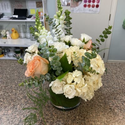 White and peach roses with cream hydrangeas in a green vase.
