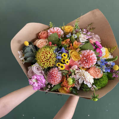 Mixed bouquet of colorful flowers wrapped in brown paper