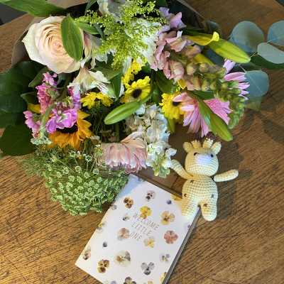 Mixed pastel bouquet with a crocheted giraffe and a welcome card