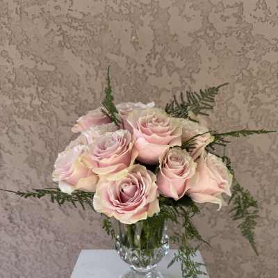 Pink roses arranged in a clear glass vase with airy greenery