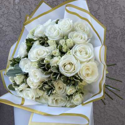 Bouquet of white roses wrapped in white paper with gold trim