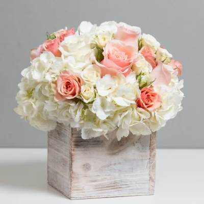 Pink and white roses arranged in a rustic wooden box