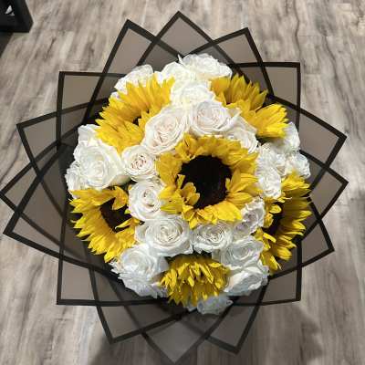 Bouquet of white roses and yellow sunflowers wrapped in black paper