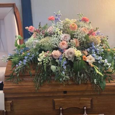 Large pastel floral arrangement on a wooden casket