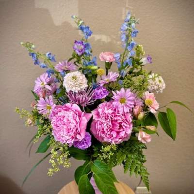 Pink peonies and purple-blue mixed flowers in a pink vase