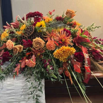 Large casket spray with orange, red, and yellow flowers