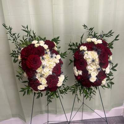Two large floral standing sprays with red and white blooms on black easels