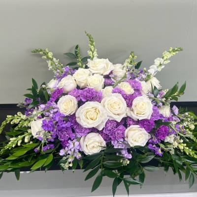 White roses and purple flowers arranged in a low centerpiece