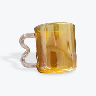 Amber glass mug with a clear handle on a white background