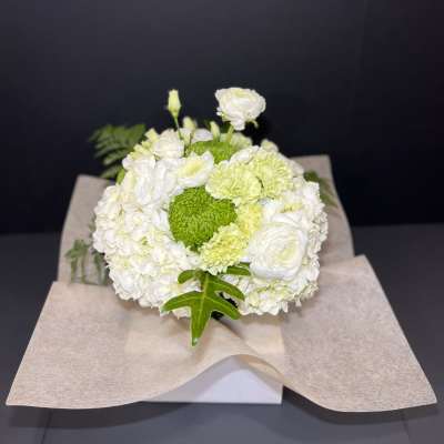 White and green floral bouquet wrapped in beige paper