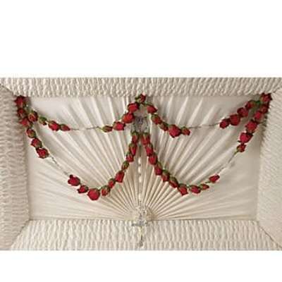 Garlands of small red roses draped inside an ivory casket lid with a crystal cross.