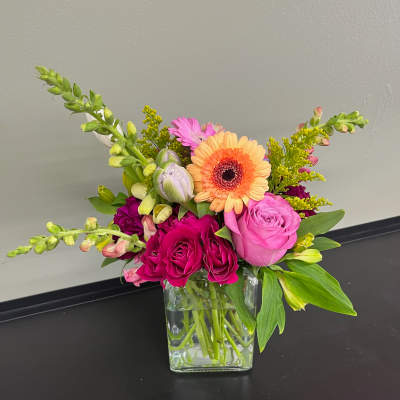 Mixed bouquet in a clear glass vase with pink and orange blooms