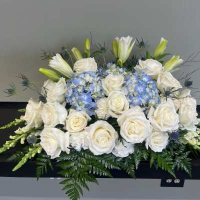 White roses and blue hydrangeas arranged in a low centerpiece.