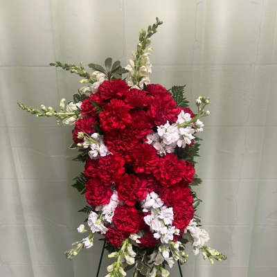 Standing floral spray of red and white carnations on a black easel