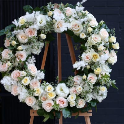 Large floral wreath of pale roses and white blooms on a wooden easel
