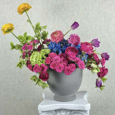 Colorful mixed flower arrangement in a gray urn vase