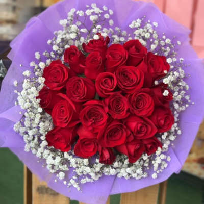 Bouquet of red roses with white baby's breath wrapped in purple paper