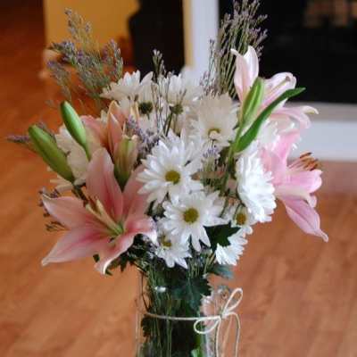 Pink lilies and white daisies arranged in a clear glass vase