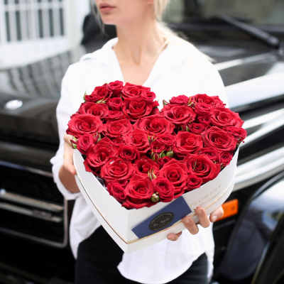 Heart-shaped box of red roses held by a person