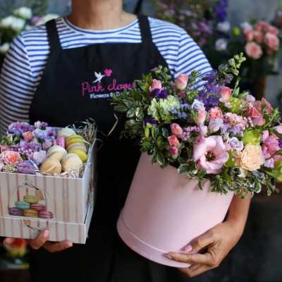 Person holding a pink flower box and a box of macarons