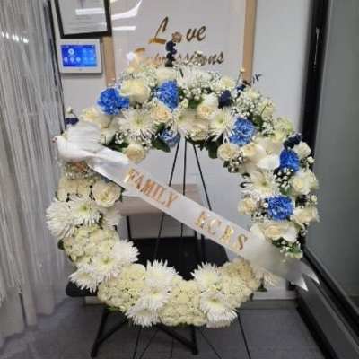 Large floral wreath with white and blue flowers on a stand