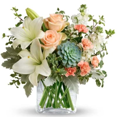 Bouquet of white lilies, peach roses, and carnations in a clear glass vase