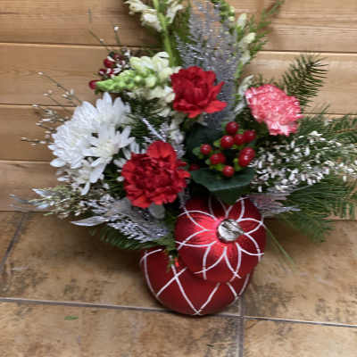 Holiday floral arrangement with red and white blooms and red ornaments