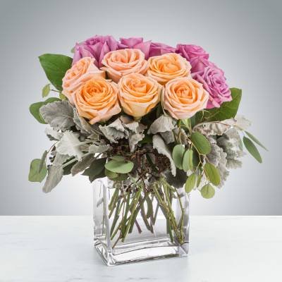 Pink and peach roses arranged in a clear square vase