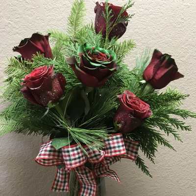Bouquet of dark red roses with evergreen and a plaid ribbon in a glass vase