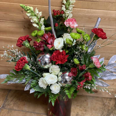 Red and white floral arrangement in a burgundy vase with silver accents