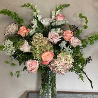 Pink and white roses with hydrangeas in a clear glass vase