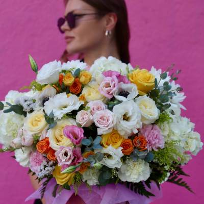 Large bouquet of mixed roses and white blooms in pink wrapping