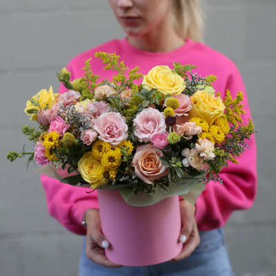 Mixed bouquet of pink and yellow roses in a pink hatbox