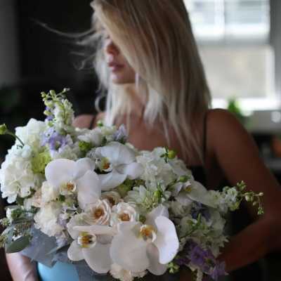 Woman holding a large bouquet of white and lavender flowers