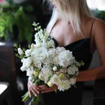 Woman holding a white bridal bouquet of roses and dahlias