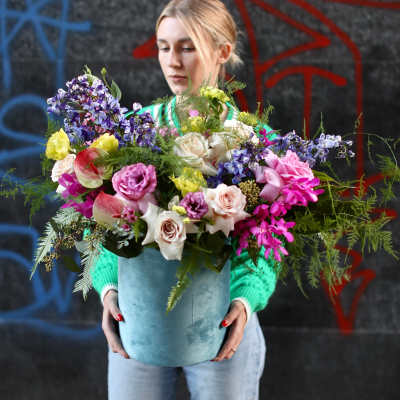 Woman holding a large mixed bouquet in a blue container