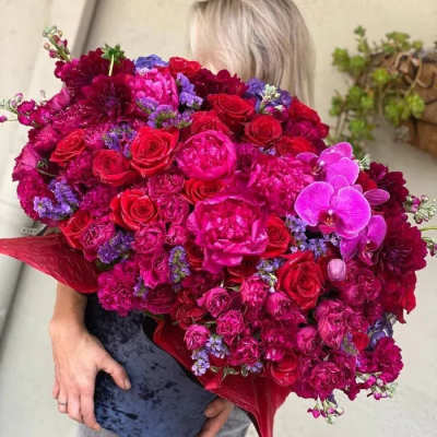 Large bouquet of red, pink, and purple flowers held by a person