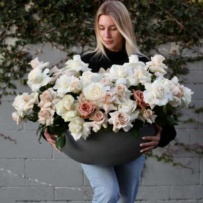 Large arrangement of white and blush roses in a dark bowl vase